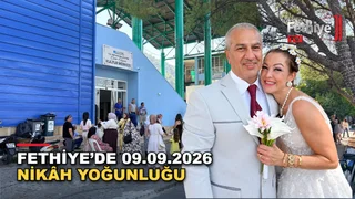 Hüseyin ve Şebnem Gücek çifti, Fethiye Belediyesi Nikah Salonu'nda nikah memuru önünde evlilik cüzdanlarını tutarak poz veriyor.